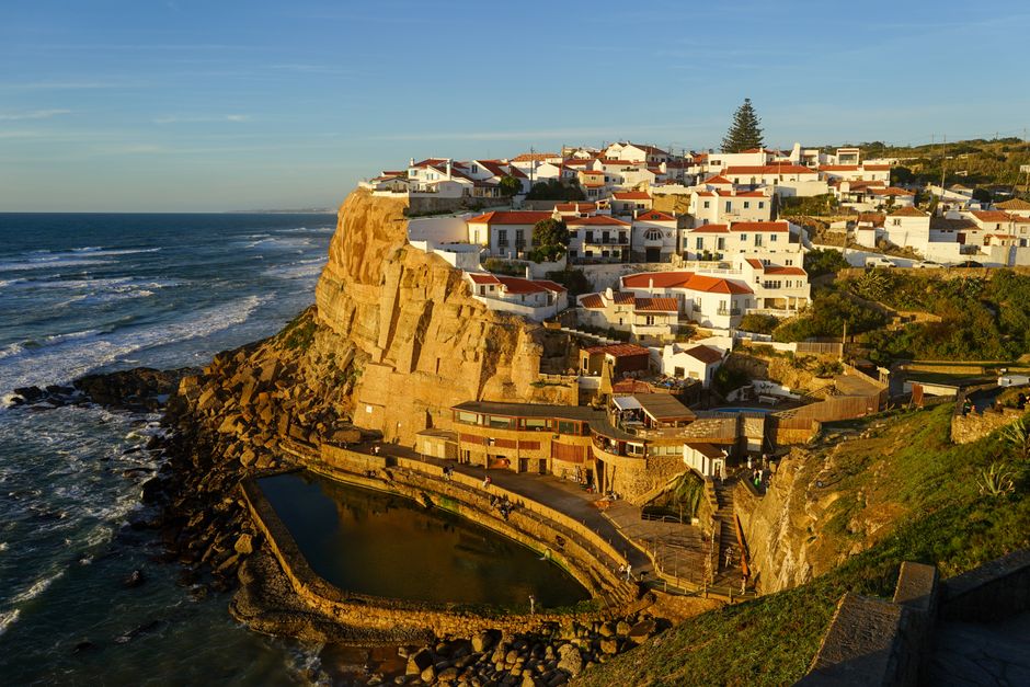 Scenic view of Azenhas do Mar, Portugal during sunset, with whitewashed houses on the cliff overlooking the ocean.