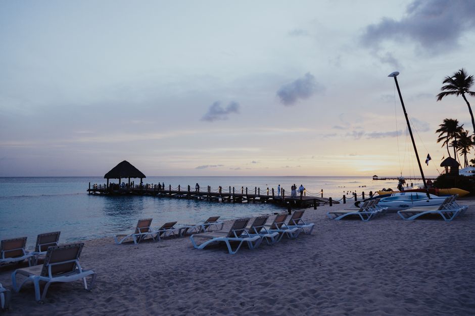Relaxing beach scene with sunbeds and pier during sunset, perfect for travel inspiration.