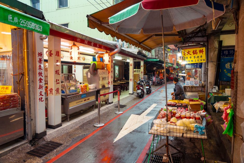 Colorful street market with food stalls and merchandise in an Asian city.