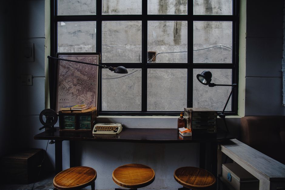 A nostalgic workspace featuring a typewriter, map, and industrial window setting.