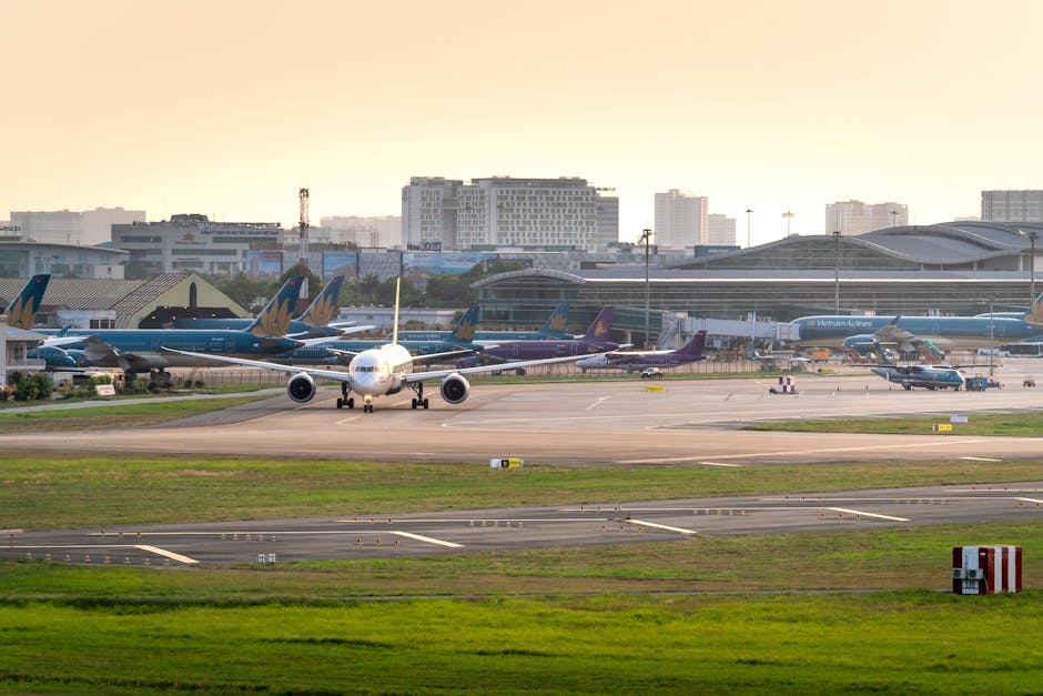 A bustling airport scene with multiple airplanes and a cityscape backdrop at sunset.