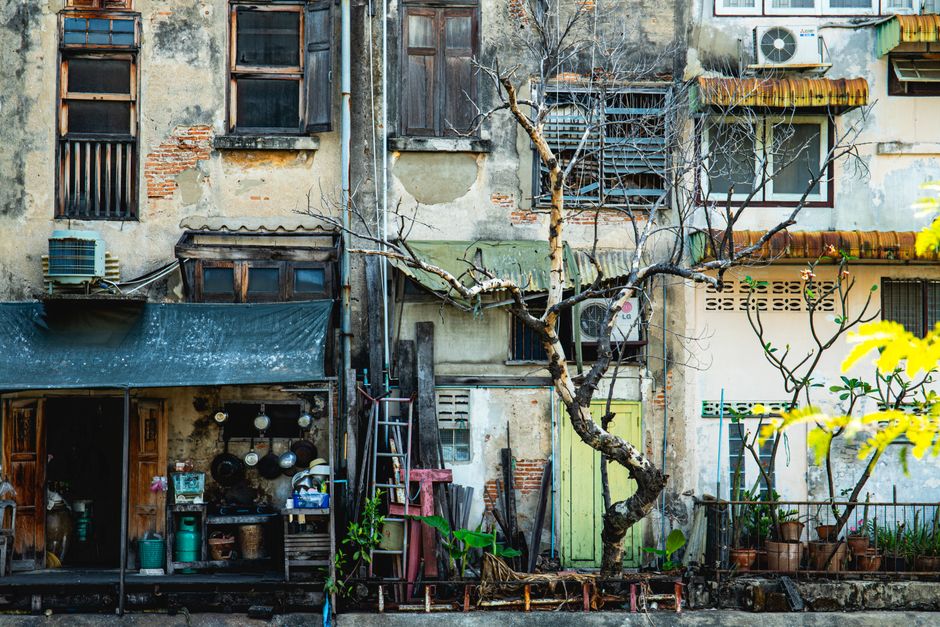 Weathered building in Bangkok with vintage charm, featuring aged walls and a potted plant.