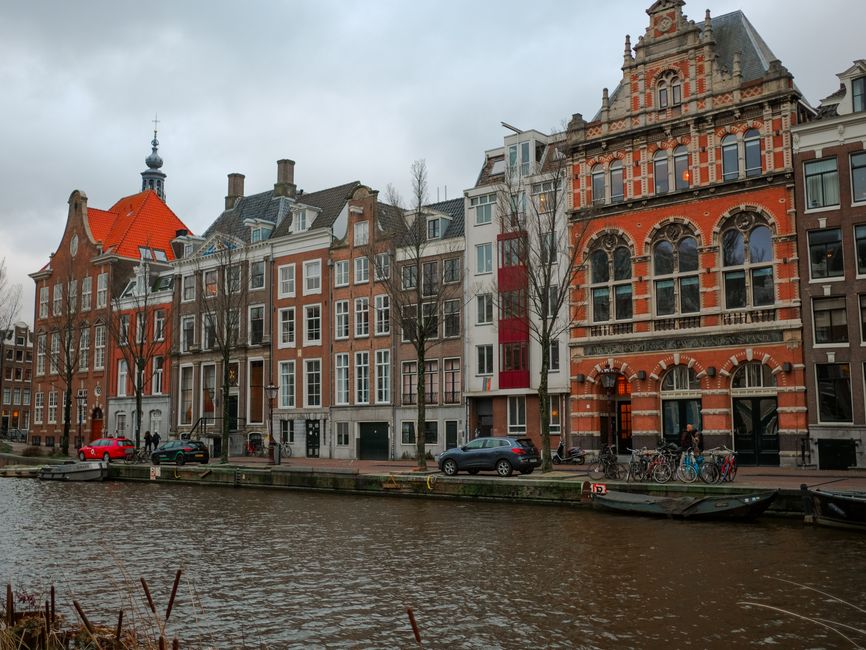 Picturesque Amsterdam canal lined with historic red-brick rowhouses and bikes.