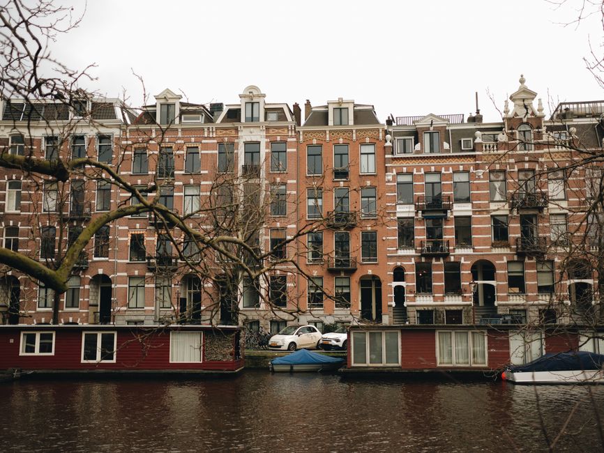 Traditional buildings line a picturesque canal in Amsterdam, showcasing iconic Dutch architecture.