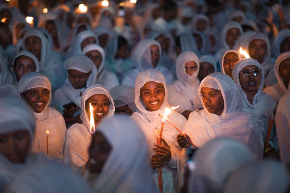 Women dressed in white participate in a vibrant candlelight ceremony in Addis Ababa, Ethiopia.