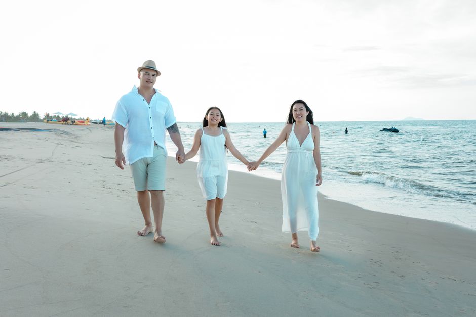 A family enjoys a leisurely walk on the beach in Hội An, Vietnam, during a summer day.