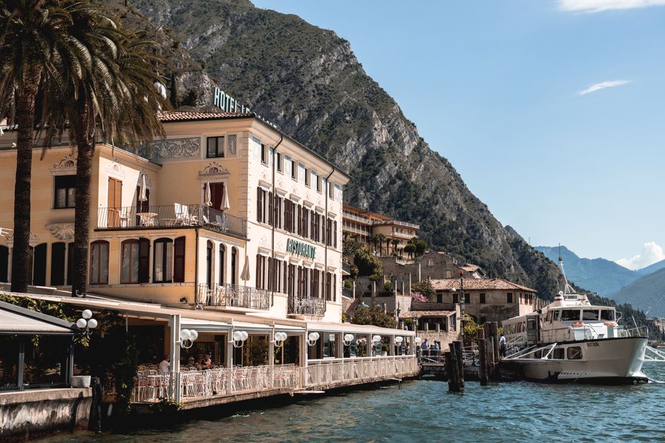 Charming lakefront hotel and restaurant in Lake Garda, Italy with stunning mountainous backdrop.