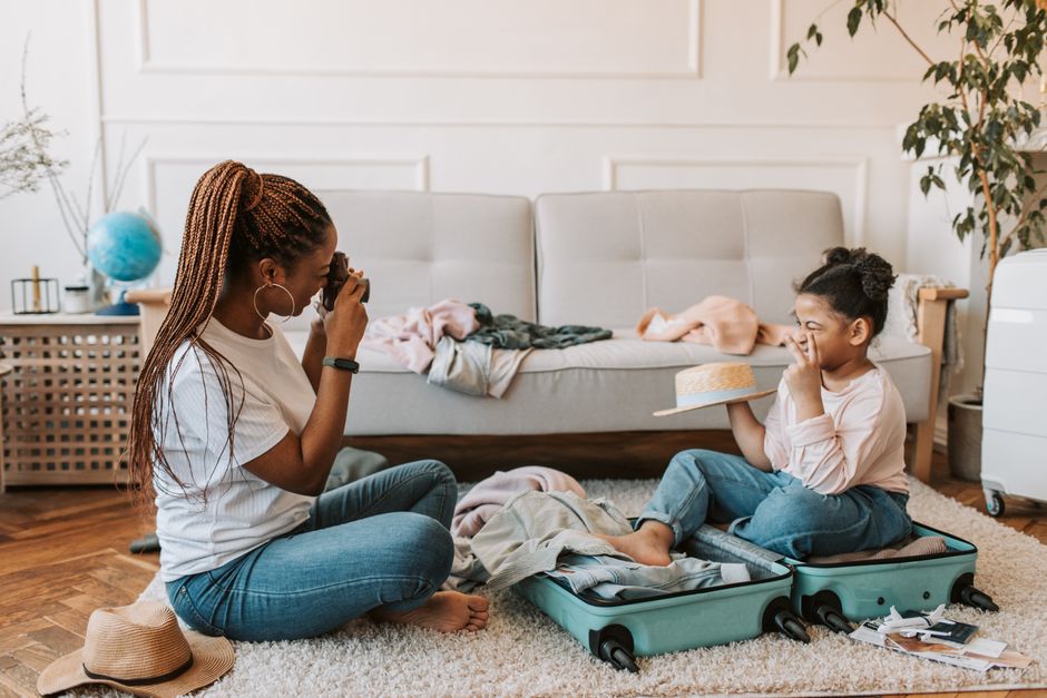 Heartwarming photo of mother and daughter taking pictures and packing indoors.