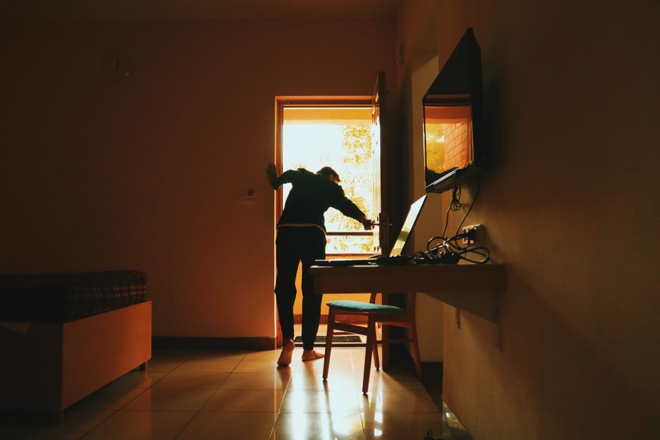 A silhouetted woman stands near a sunlit door in a modern interior, creating a warm ambiance.