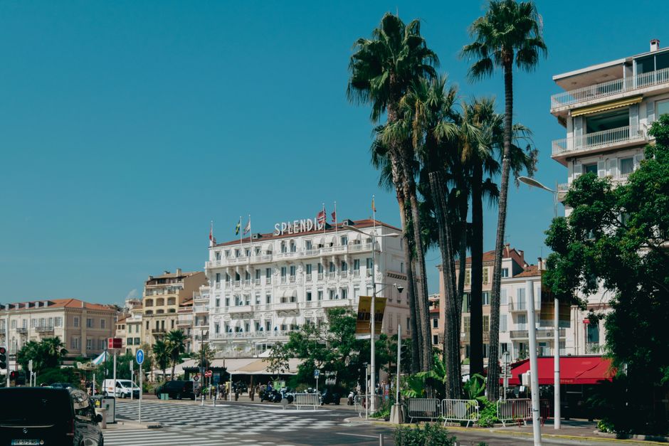 View of the iconic Splendid Hotel in Cannes amidst palm trees on a sunny day.