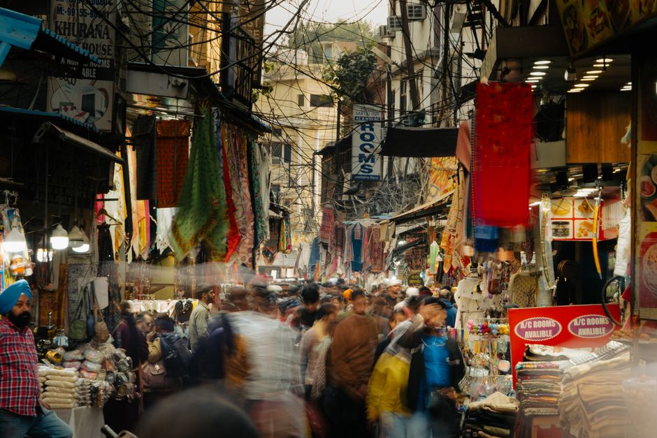Vibrant street market in India with colorful fabrics and bustling crowds.