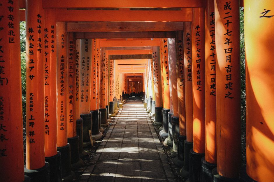 Explore the captivating orange torii gates of Fushimi Inari Taisha in Kyoto, Japan, bathed in sunlight.