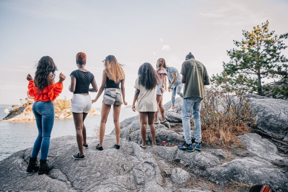 A group of friends having fun on rocky shore in a summer setting, enjoying leisure time outdoors.