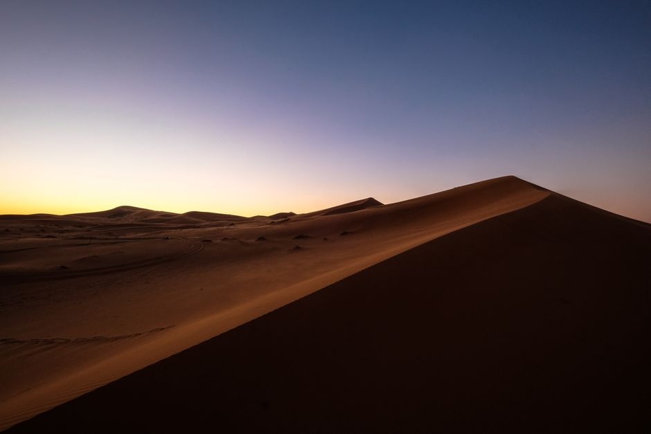 Breathtaking view of sand dunes under a colorful sunset in the Moroccan desert.