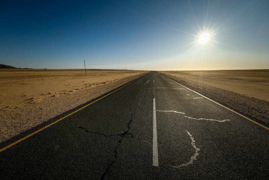 A lone highway stretches through a sunlit desert landscape, offering a sense of endless travel.