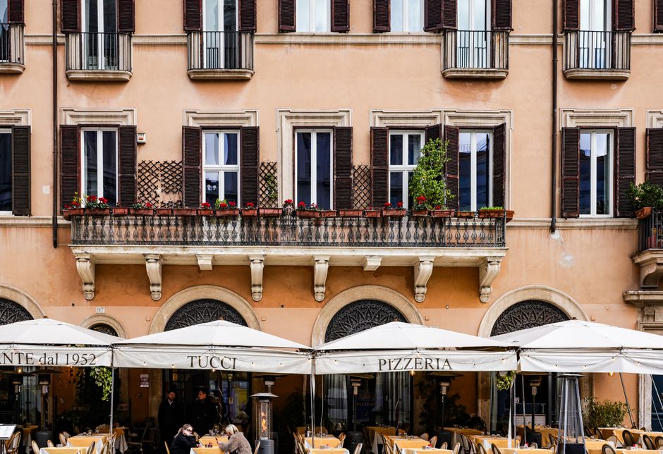 Cozy Italian café under historic architecture offering a vibrant city street atmosphere.