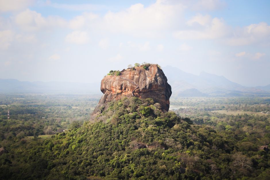 View of the iconic Sigiriya Rock Fortress, surrounded by lush vegetation in Sri Lanka.