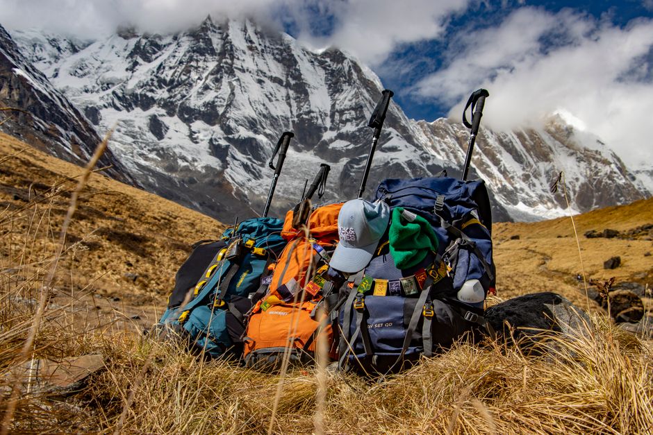 Backpacks rest at Annapurna's base under the snowy peaks, capturing trekking adventure in Nepal.