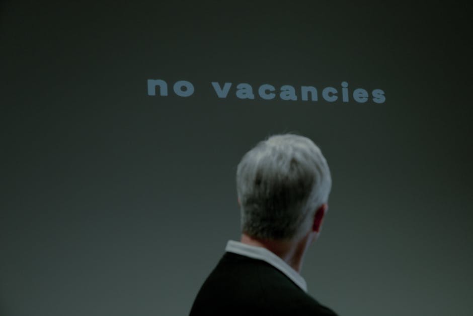 Senior man facing a 'No Vacancies' sign symbolizing job search challenges and ageism.